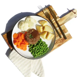 Rissole with gravy, roast potatoes, carrots, peas, and cauliflower