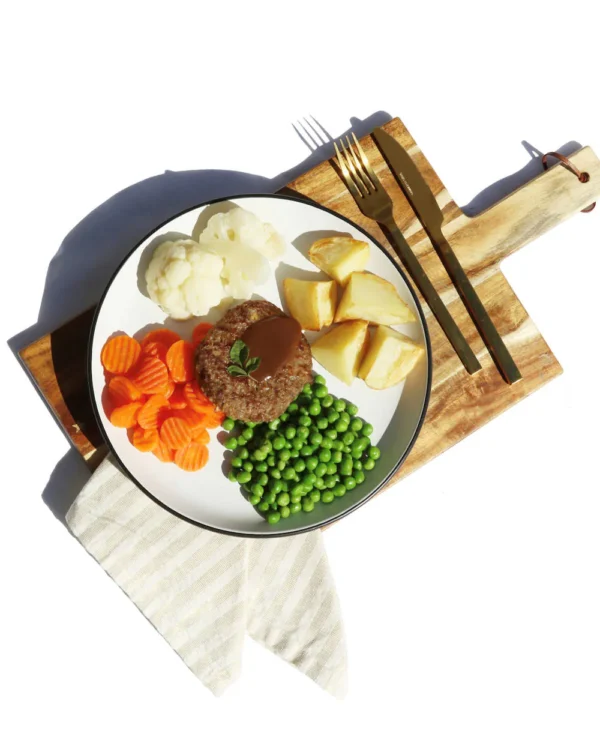 Rissole with gravy, roast potatoes, carrots, peas, and cauliflower